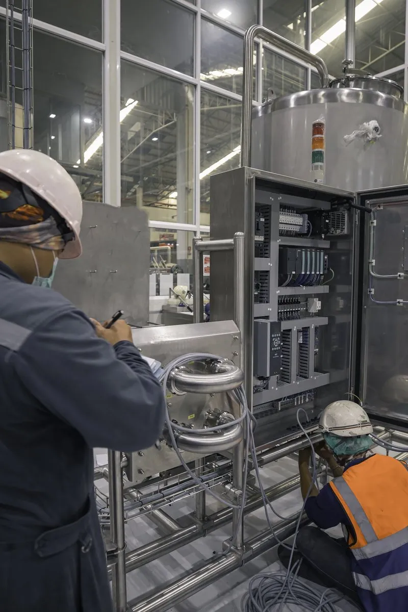 An electrician testing an electrical box on an industrial site.